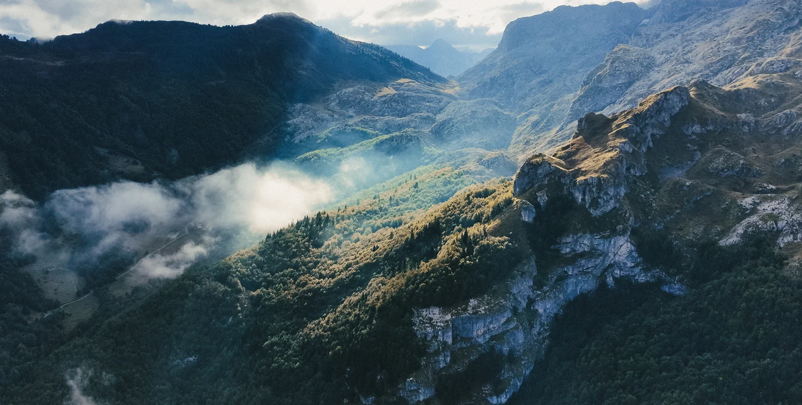 Vista aérea de un valle con niebla iluminada entre montañas